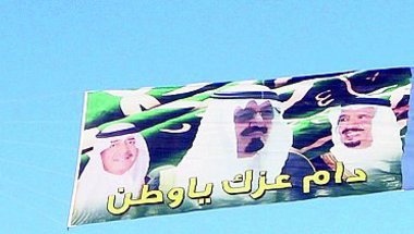 العلم السعودي يستعرض بصورة خادم الحرمين